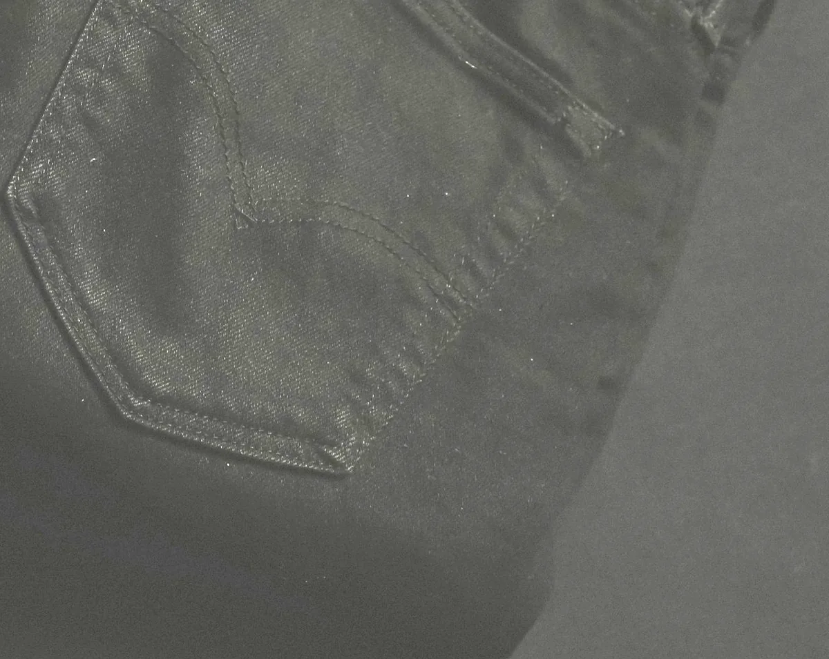 Back pocket and topstitching detail on a pair of black denim jeans